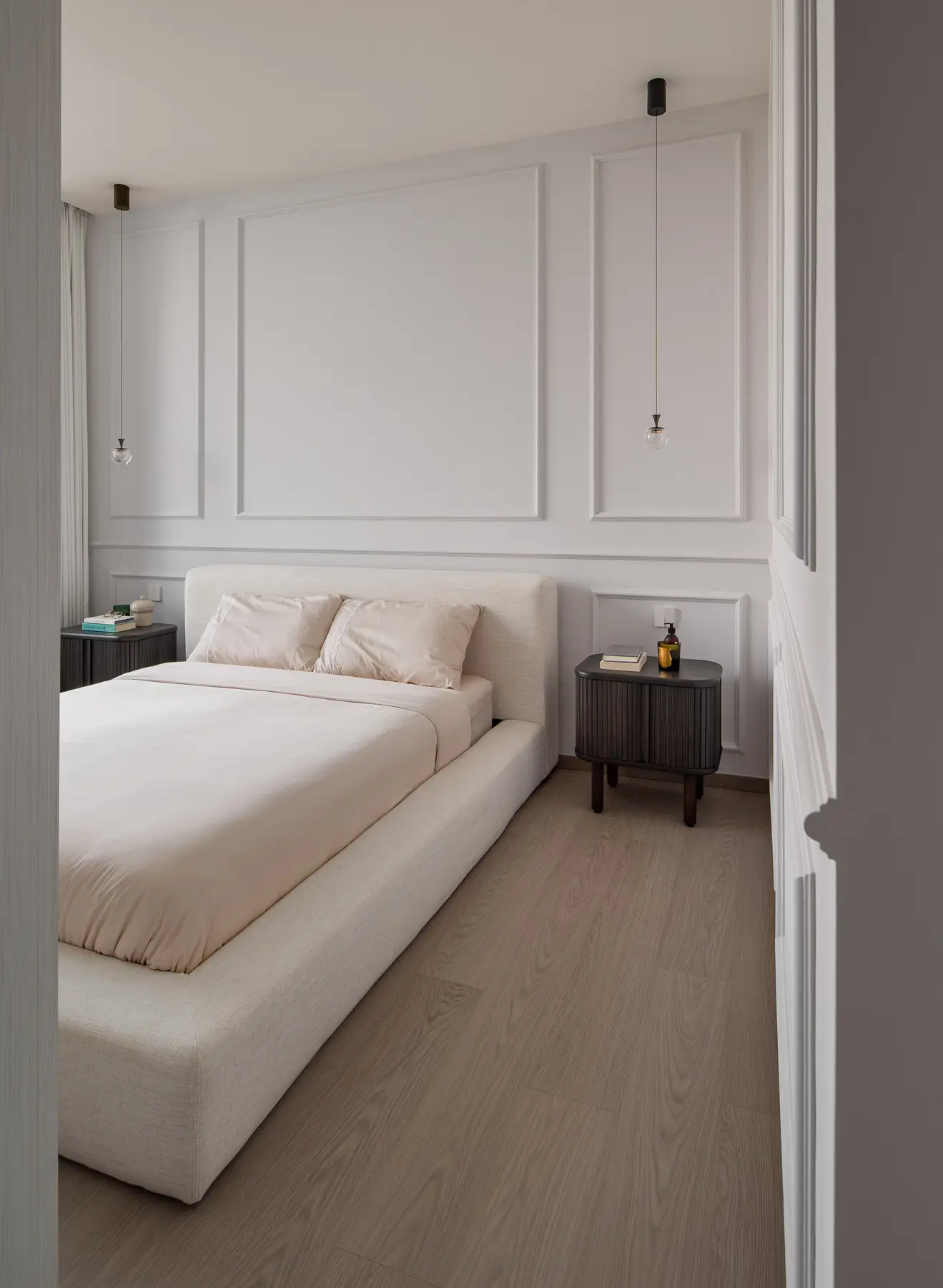 Secondary bedroom — white panel moulding headboard with glass pendant lights and dark bedside tables