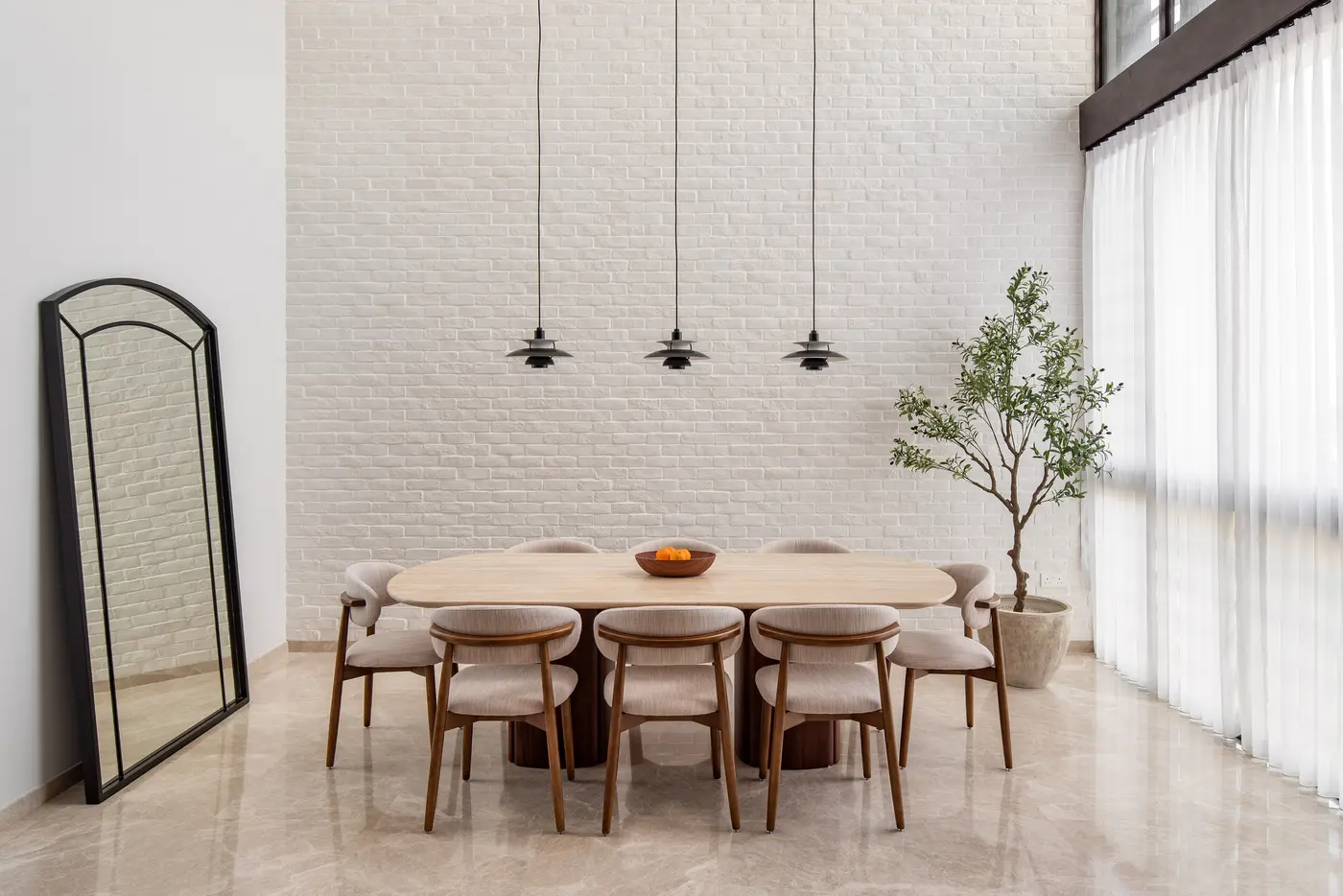 Wide view of dining space with olive tree and full-height bricks