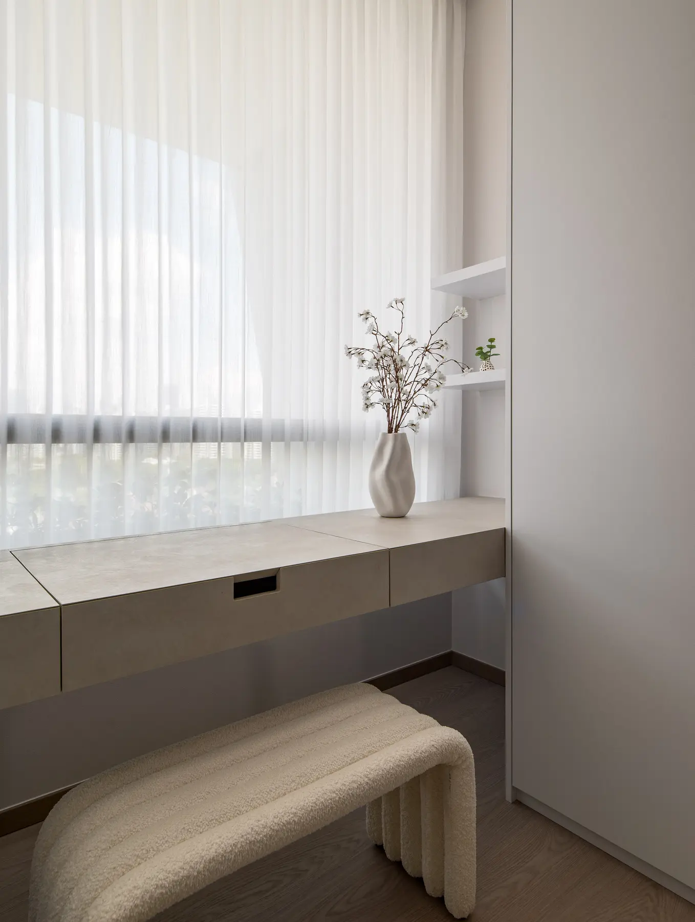 Walk-in wardrobe — floating dressing table with ceramic vase, sheer curtains and city view beyond
