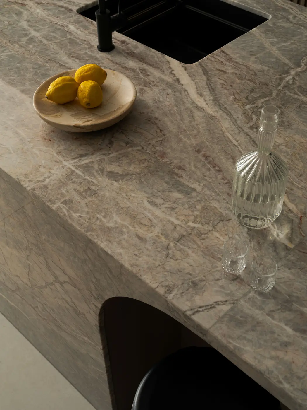 Kitchen island close-up — marble surface with lemons and glass carafe