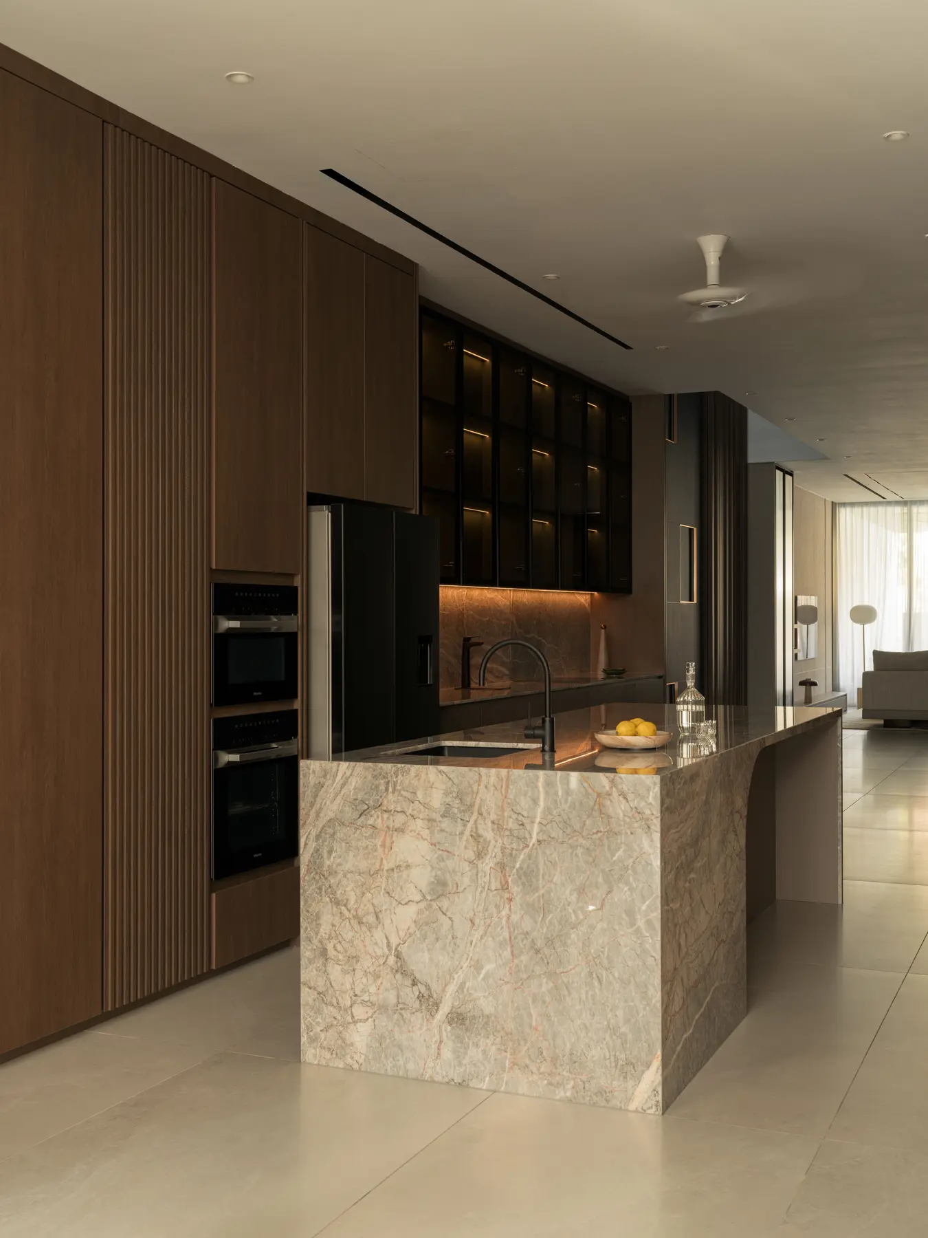 Kitchen — Flor de Pesco marble island, dark glass upper cabinets and integrated lighting