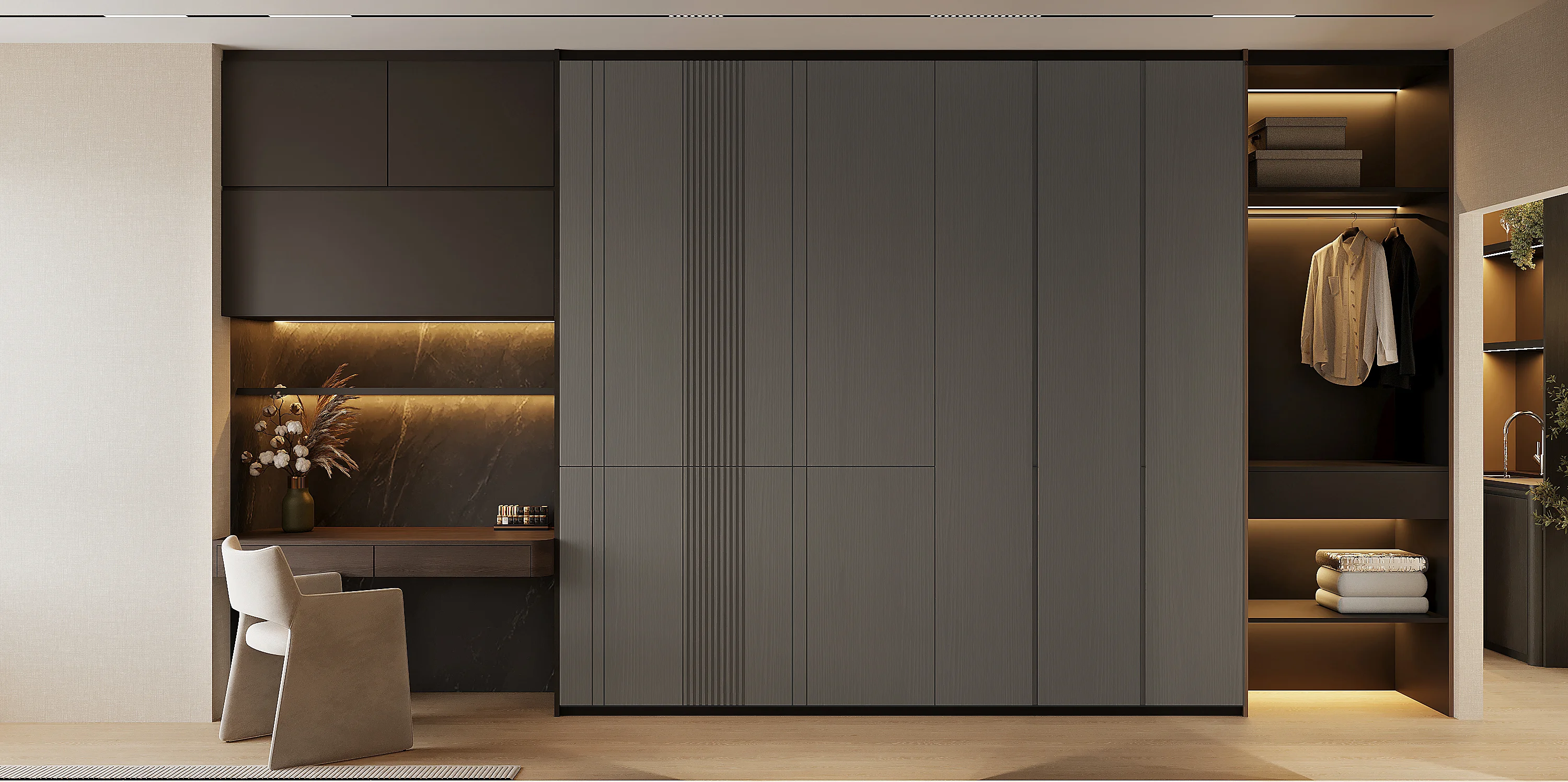 Dressing area — full-height fluted wardrobe doors beside a vanity counter with dark stone backsplash, warm recessed lighting and open wardrobe section revealing hanging garments
