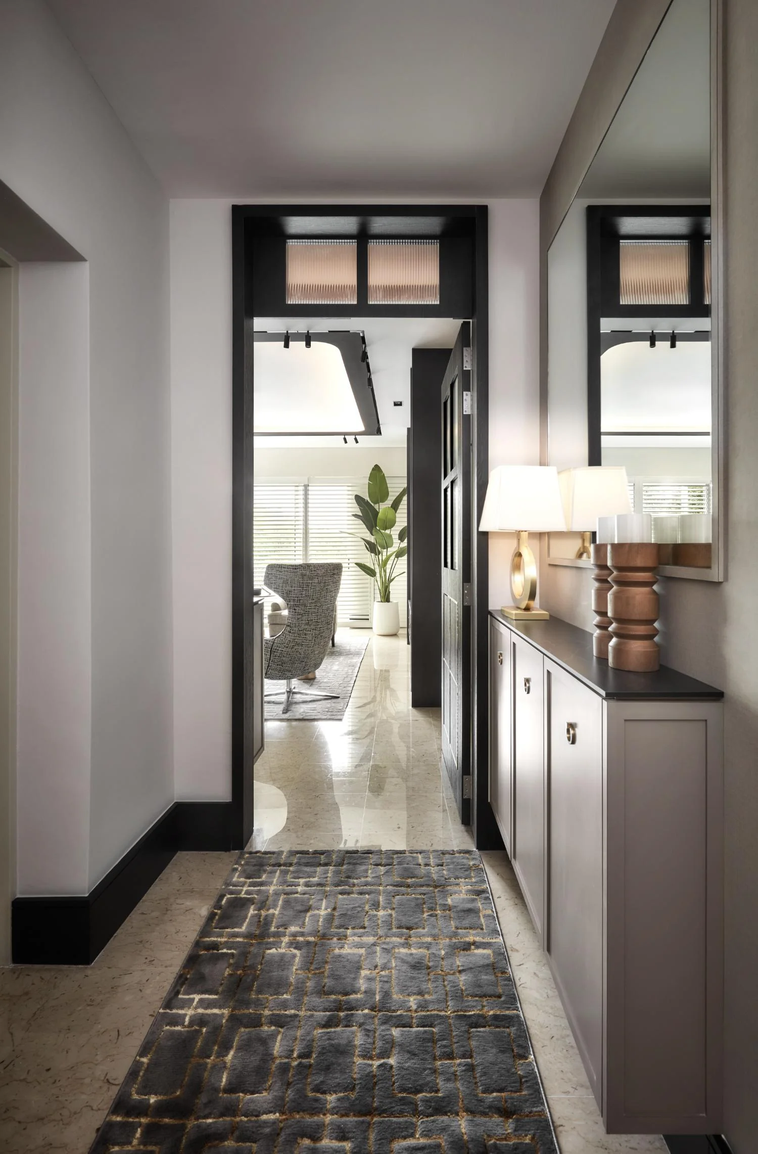 Foyer — console, lamp, mirror and corridor establishing the home's material register on arrival