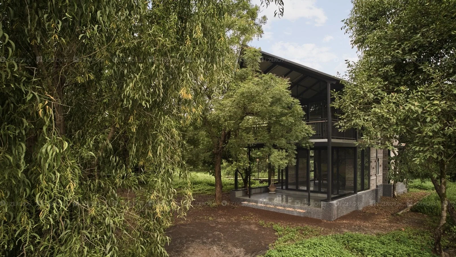 farmPAD exterior — dark steel structure and full-height Tostem glazing set within the established landscape, ground-floor verandah visible