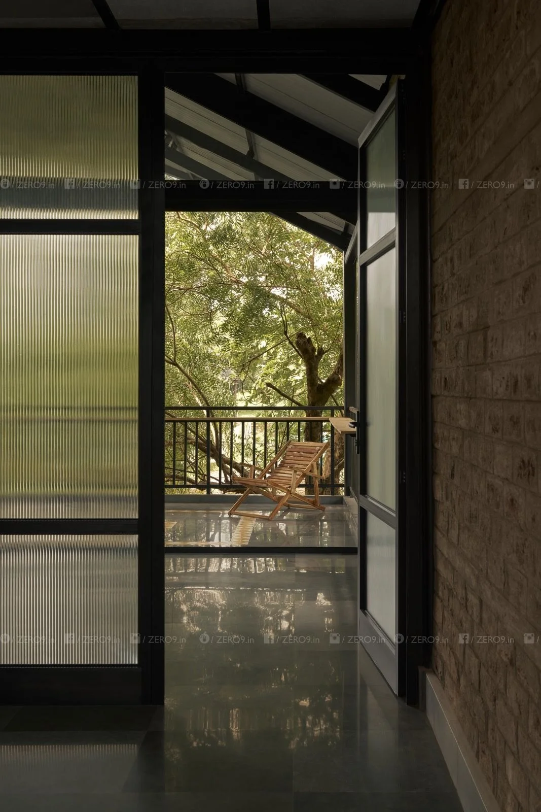 View from the interior through a glazed door toward the balcony and surrounding forest canopy